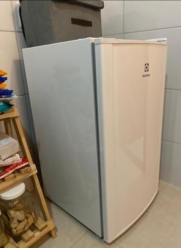 um frigorífico branco numa cozinha ao lado de uma prateleira em Casa com excelente acomodação em Itatiaia