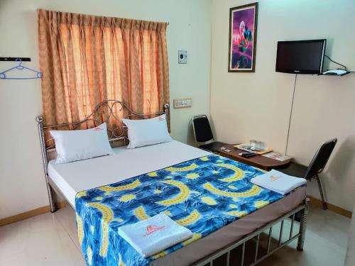 a bed in a room with a desk and a bed sidx sidx sidx at DPD Beach Hotel in Puducherry