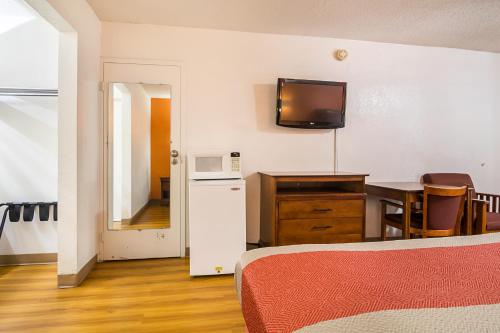 a room with a bed and a table and a tv on the wall at Motel 6-Conyers, GA in Conyers