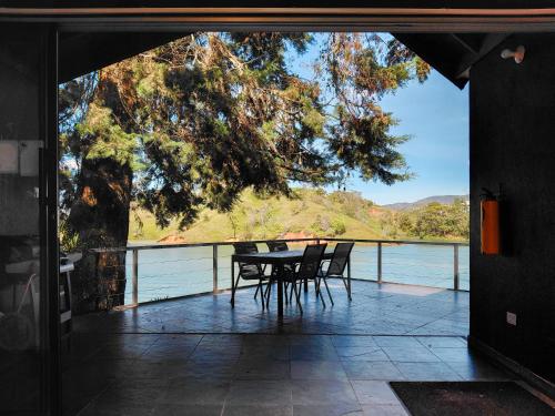 ein Tisch und Stühle auf einem Balkon mit Blick auf das Wasser in der Unterkunft Cottage on the Lake - Cabaña privada - Guatapé - Jacuzzi in Guatapé