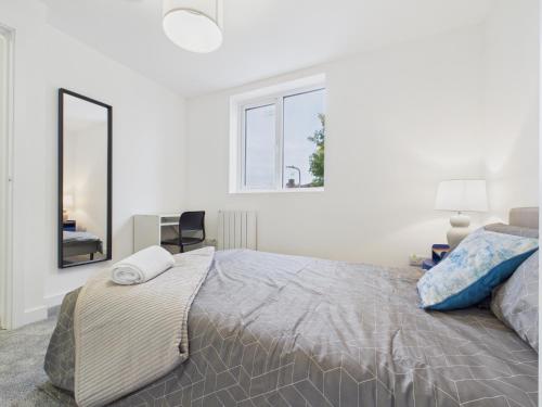 a white bedroom with a large bed and a mirror at Green Hat Stays Newport City in Newport
