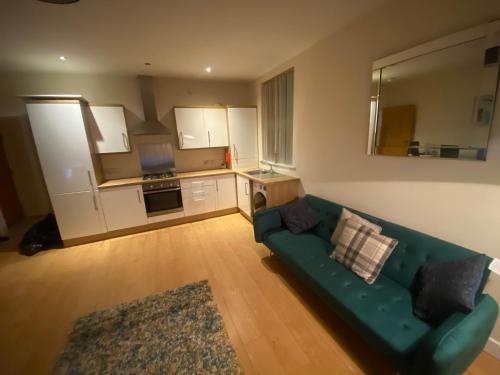 ein Wohnzimmer mit einer grünen Couch und einer Küche in der Unterkunft vancouver place 10 min from city center and close to all shops in Belfast