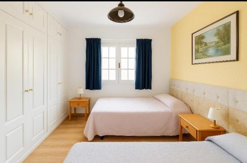a bedroom with two beds and a window with blue curtains at Loma Estrella Ocean Suite Upper Arguineguín in Arguineguín