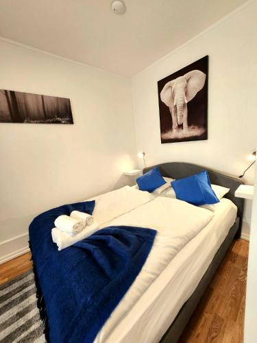 Dali 3 Ultra Central Stavanger City في ستافانغر: غرفة نوم بسرير كبير مع ملاءات زرقاء وصورة فيل