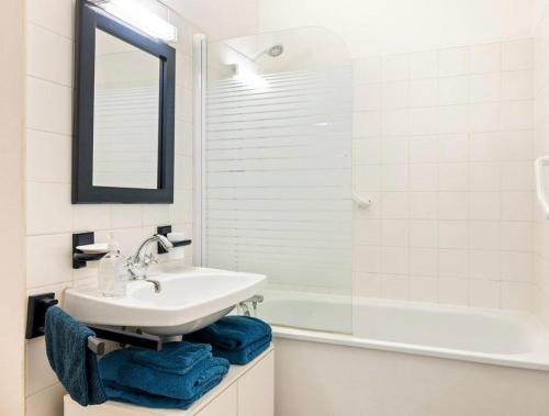 een badkamer met een wastafel, een spiegel en een bad bij La petite boucane in Fécamp