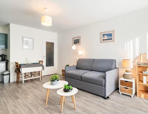 een woonkamer met een bank en twee tafels bij La petite boucane in Fécamp