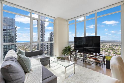 a living room with a large tv and large windows at Ultra Luxurious 2.5 Bedroom 2 Full Bathroom 1 Parking Condo Near SQ1 Striking Views in Mississauga