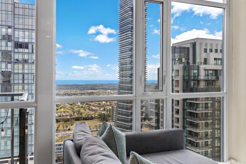 a living room with a couch and a large window at Ultra Luxurious 2.5 Bedroom 2 Full Bathroom 1 Parking Condo Near SQ1 Striking Views in Mississauga
