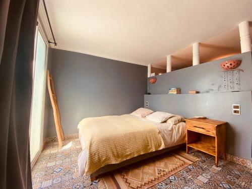 a bedroom with a bed and a wooden table at Charming room with balcony and ocean view in Essaouira
