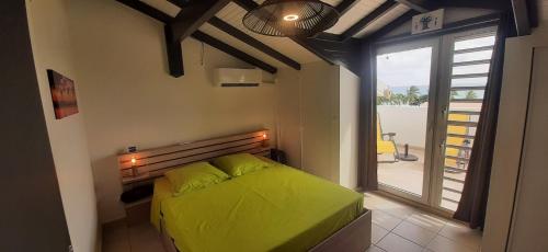 a bedroom with a green bed and a large window at Beau duplex T3 avec une superbe vue mer in Le Diamant