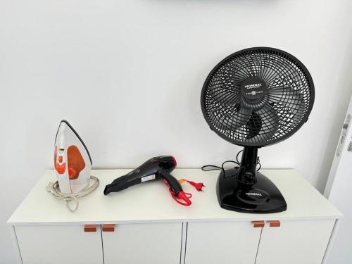 a fan sitting on top of a white cabinet at Cozy apartment near the airport in São José dos Pinhais