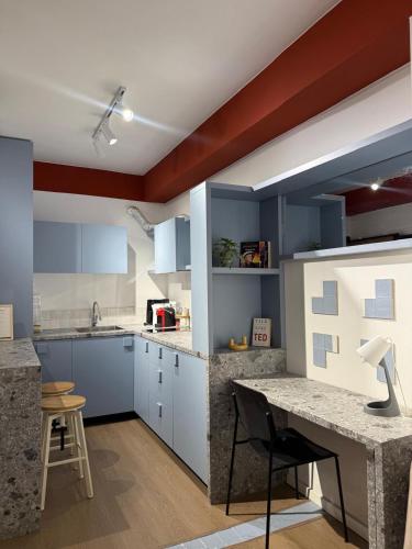 kuchnia z niebieskimi szafkami i biurkiem w środku w obiekcie Central Apartment Prishtina w Prisztinie