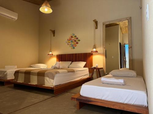 a bedroom with two beds and a mirror at Pousada Barra Nova Praiamar in Cascavel