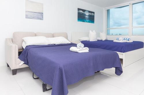 two beds in a white room with purple sheets at UNIT #908 Castle Beach Club Condominium in Miami Beach