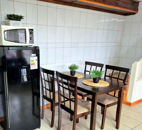 een keuken met een tafel met stoelen en een magnetron bij Departamento bahia fonck in Puerto Montt