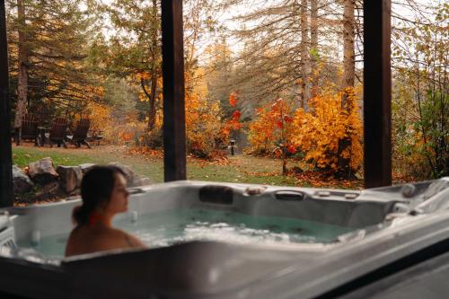 Eine Frau sitzt in einer Badewanne vor einem Fenster in der Unterkunft Chalet Mazama - Private Lake - Hot Tub - 16P in Wentworth-Nord