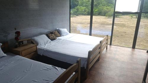 two beds in a room with a large window at family home in Honda