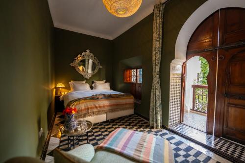 a bedroom with a bed and a table and a window at Riad Les Yeux Bleus in Marrakesh