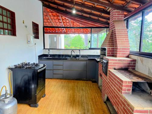 uma cozinha com um fogão e um lavatório num quarto em Chácara com piscina e lago aconchegantes em Planaltina