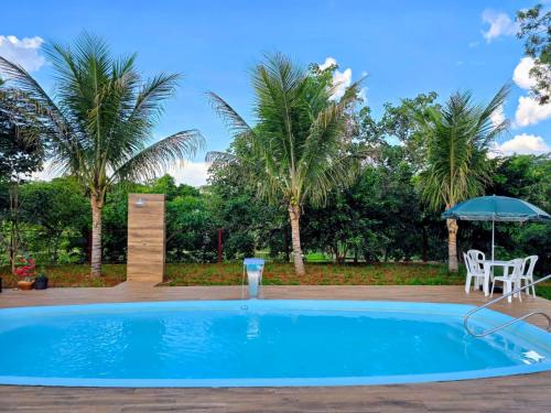 uma piscina com uma mesa e um guarda-sol em Chácara com piscina e lago aconchegantes em Planaltina