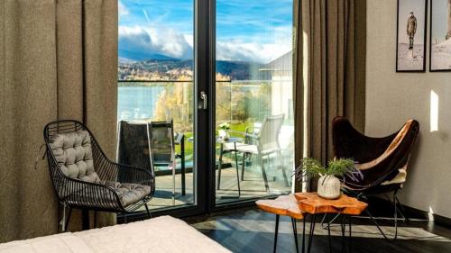 a living room with chairs and a balcony with a view at Woda i góry - studio z widokiem na góry i zalew in Sosnówka