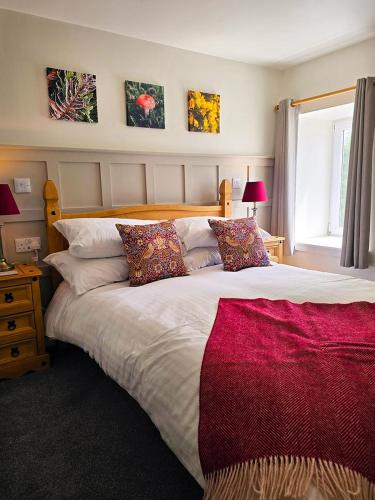 a bedroom with a large bed with a red blanket on it at The Wigtown Ploughman in Wigtown