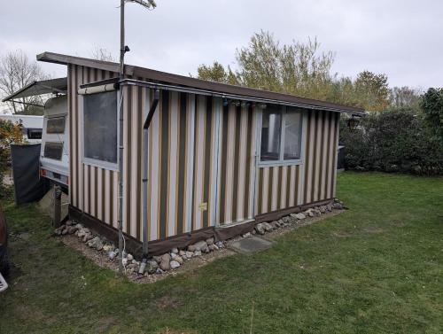 een klein huisje in een tuin naast een busje bij Wohnwagen mit feststehendem Vorzelt in Fehmarn