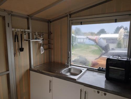 una cucina con lavandino e una finestra in un rimorchio di Wohnwagen mit feststehendem Vorzelt a Fehmarn