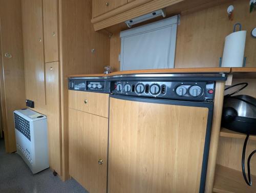 a kitchen with wooden cabinets and a stove at Wohnwagen mit feststehendem Vorzelt in Fehmarn