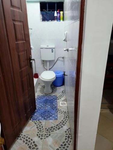 a bathroom with a toilet and a tile floor at Serene63 Studios Kenol,Muranga in Gitura