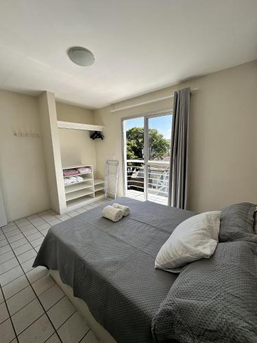 a bedroom with a large bed and a balcony at Com churrasqueira em Canasvieiras in Florianópolis