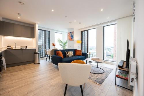 a living room with a blue couch and a kitchen at Pet friendly 2BR City Centre Apartment - Near Piccadilly in Manchester
