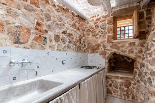La salle de bains est pourvue d'une baignoire et d'un mur en pierre. dans l'établissement Villa Petra Viva, à Ugento
