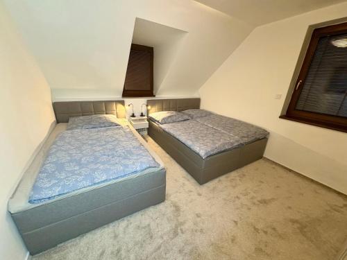 2 camas individuales en un dormitorio con ventana en Tatra Family Loft, en Vysoké Tatry