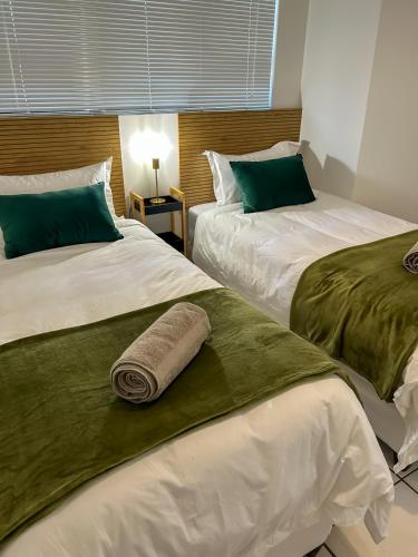 two beds in a hotel room with a towel on them at Secret Eden in Jeffreys Bay