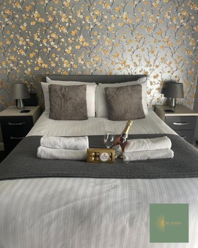 a bed with a bottle of wine and towels on it at Orlando Llandundo Apartment in Llandudno