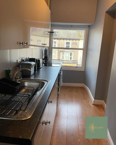 a kitchen with a counter and a sink and a window at Orlando Llandundo Apartment in Llandudno