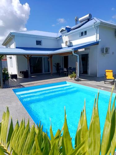 a swimming pool in front of a house at Villa Luciole Man'Néa in Sainte-Anne