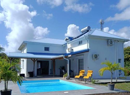 a white house with a swimming pool in front of it at Villa Luciole Man'Néa in Sainte-Anne