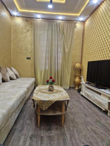 a living room with a couch and a tv and a table at Appartement spacieux au centre-ville in Tetouan