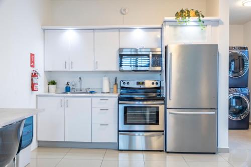 Una cocina con gabinetes blancos y un refrigerador de acero inoxidable. en Aquaville Dorado Moderna Studio 6, en Dorado