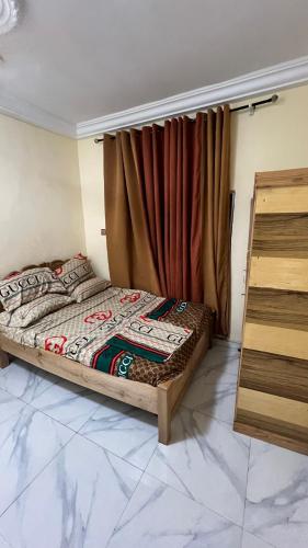 a bedroom with a bed and a window with a curtain at Prof's Villa in Kumasi