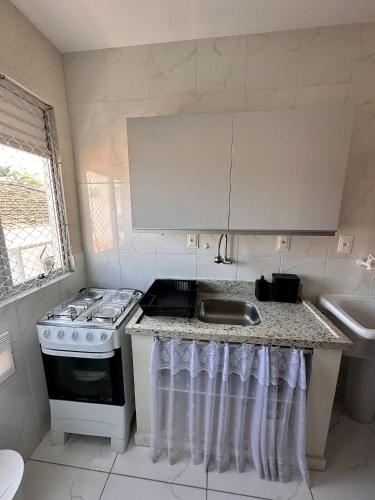 a small kitchen with a stove and a sink at Com churrasqueira em Canasvieiras in Florianópolis