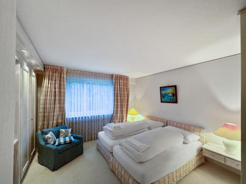 a bedroom with a bed and a chair and a window at Herrliche 3 Schlafzimmer Wohnung in Davos zentral & exklusiv in Davos