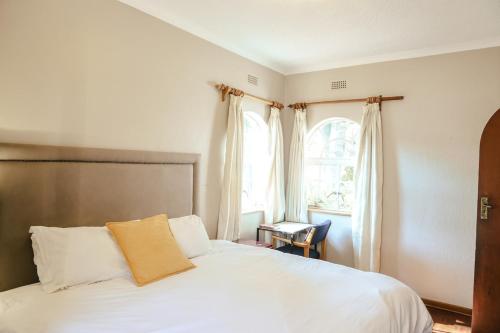 a bedroom with a white bed and a window at Borrowdale Hearthside Retreat in Harare