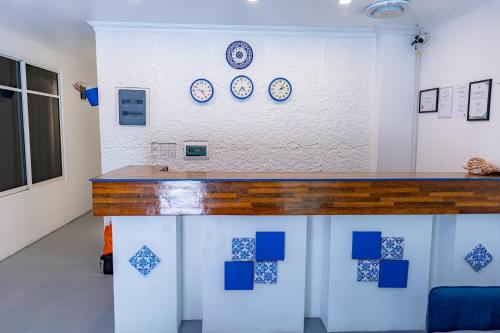eine Theke in einem Raum mit Uhren an der Wand in der Unterkunft Santorini Maafushi Maldives in Maafushi