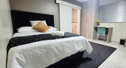 a bedroom with a large white bed and a desk at Ekuhlaleni Room 6 in Pretoria