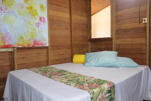 a small bedroom with a bed and a painting at Hostel IndiaJara in Itacaré
