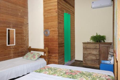 a room with two beds and a dresser in it at Hostel IndiaJara in Itacaré