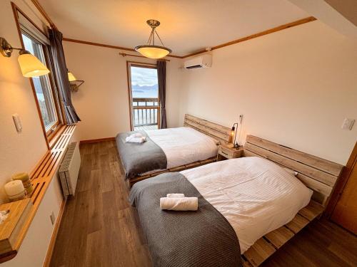 a bedroom with two beds and a window at Cloud9 Toya in Lake Toya